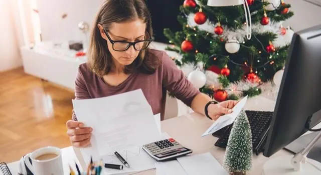 Woman sitting at her desk looking at documents with christmas decorations in the background