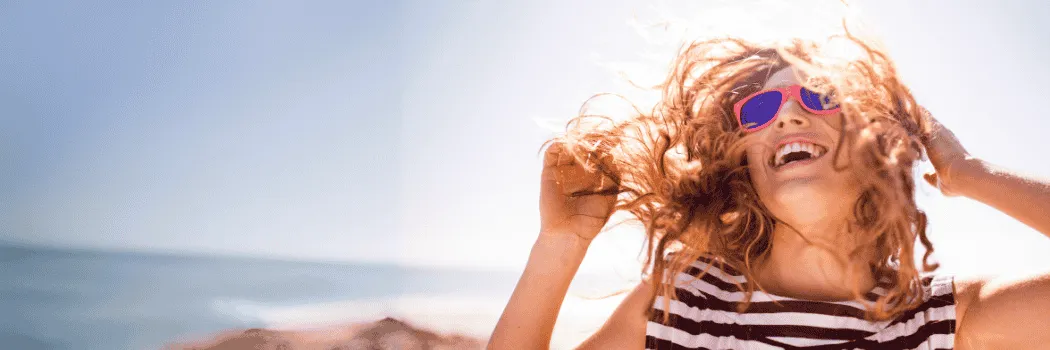 Woman at the beach smiling with sunglasses on
