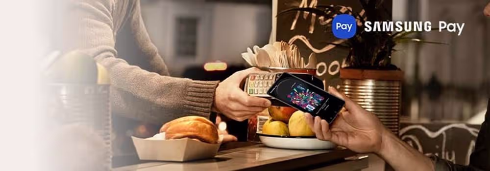 A person holding their Samsung phone to an eftopos machine to pay using Samsung Pay
