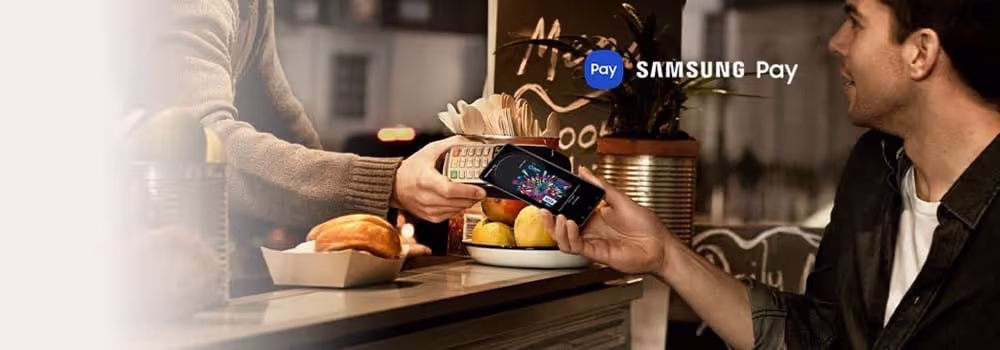 A person holding their Samsung phone to an eftopos machine to pay using Samsung Pay