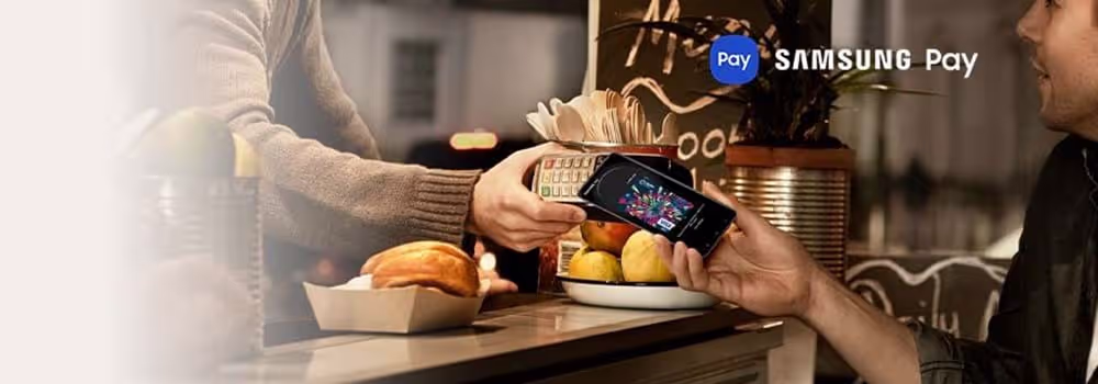 A person holding their Samsung phone to an eftopos machine to pay using Samsung Pay