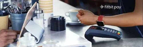 A person wearing a smartwatch putting their arm up to an eftpos machine to pay using Fitbit Pay