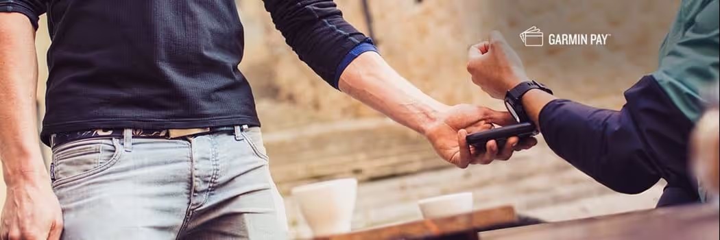 A person wearing a smartwatch putting their arm up to an eftpos machine to pay using Garmin Pay