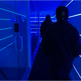 Man standing in neon blue-lit hallway – futuristic creative scene.