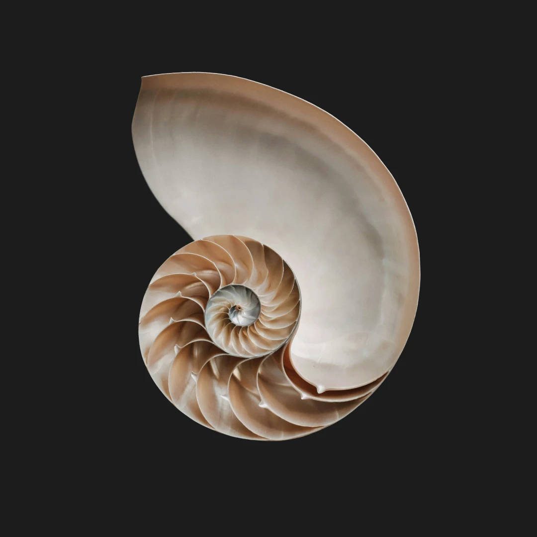 Two people wearing headphones sitting and talking into microphones in a modern podcast studio with a large illuminated G on the wall.