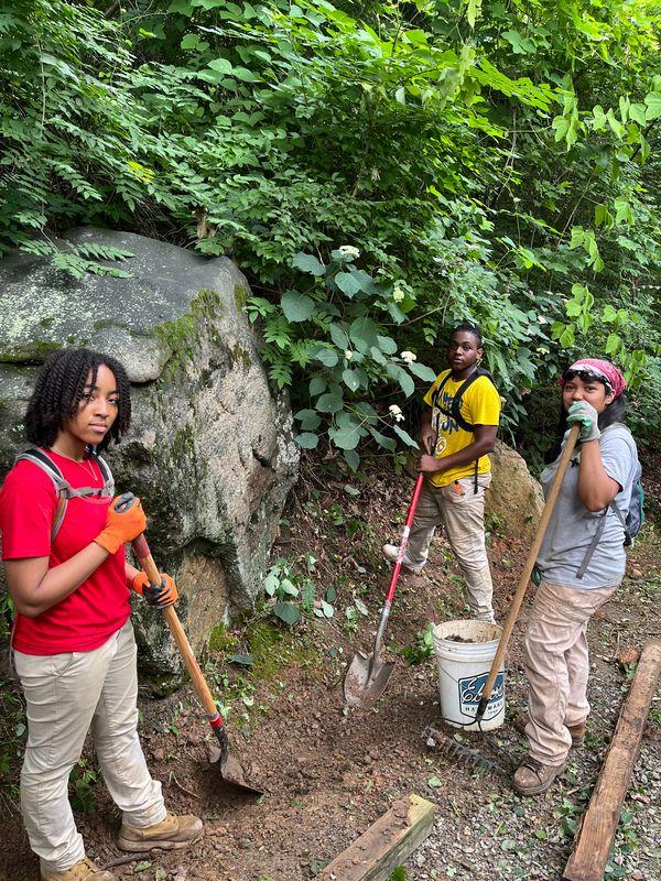 three young black teenagers posing with sho els at a worksite.