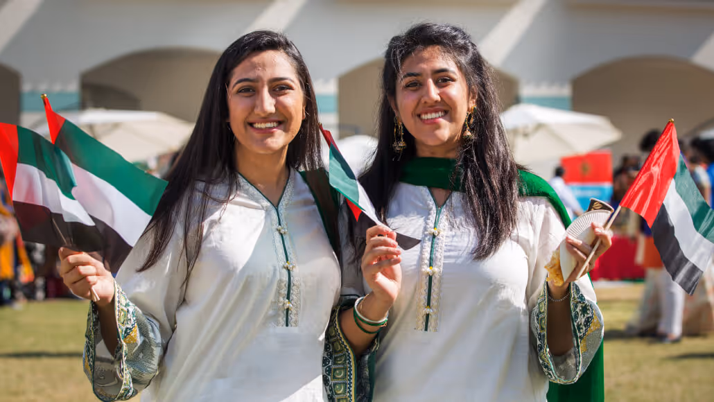 Women holding UAE flags during Dubai Knowledge Park celebration.