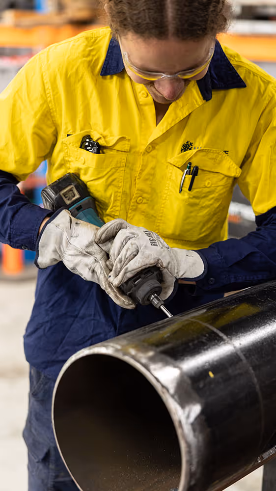 Technician in workshop handling large pipe component