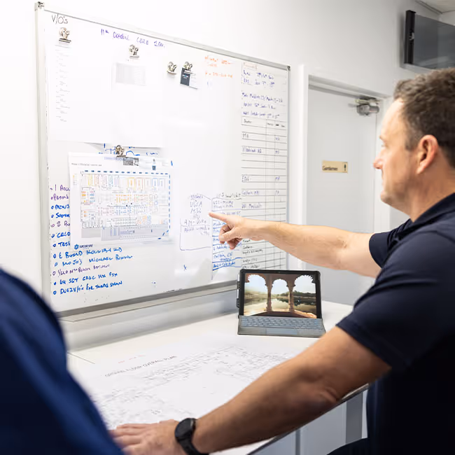 Team leader pointing at a whiteboard during a project meeting