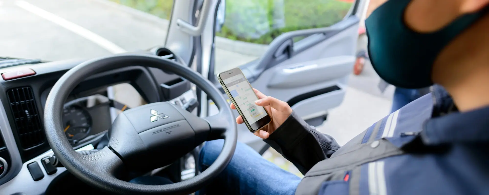 A fleet driver sitting in his driver seat while looking at his phone to access MyFuso app