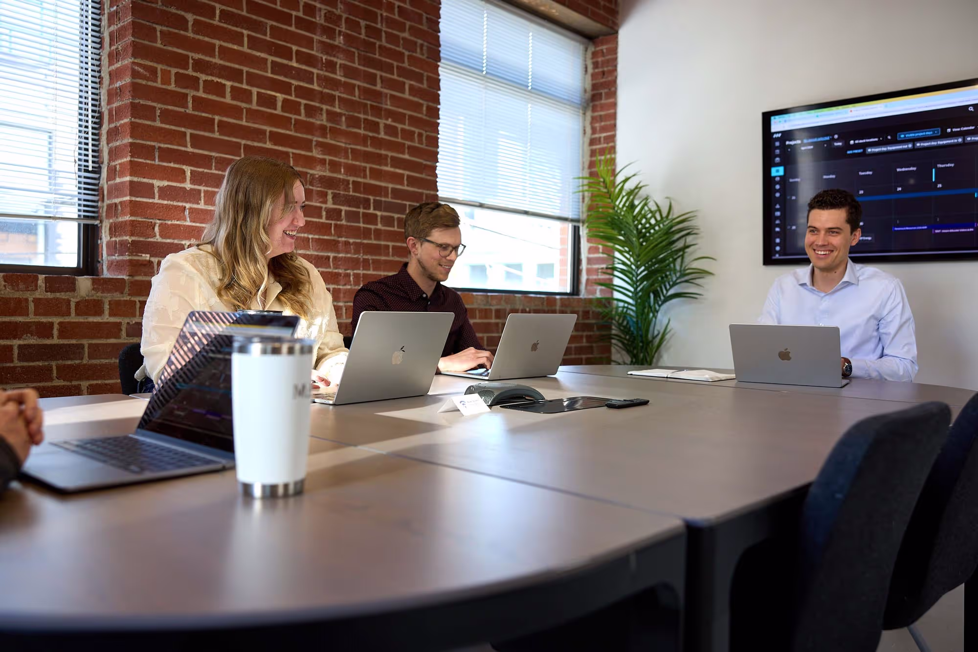 Three people collaborating around a boardroom table during a meeting, showcasing the agency's commitment to teamwork and creativity.