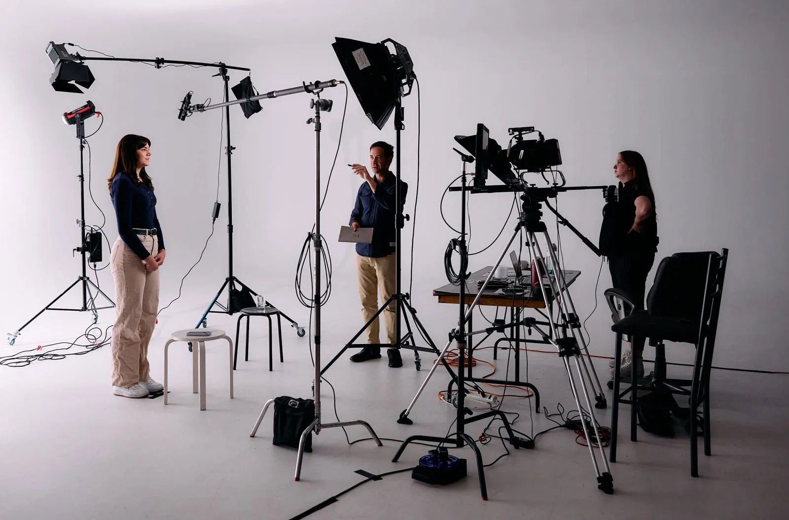 On set with the director, actor, and teleprompter operator surrounded by production gear, including lights, tripods, and cameras.