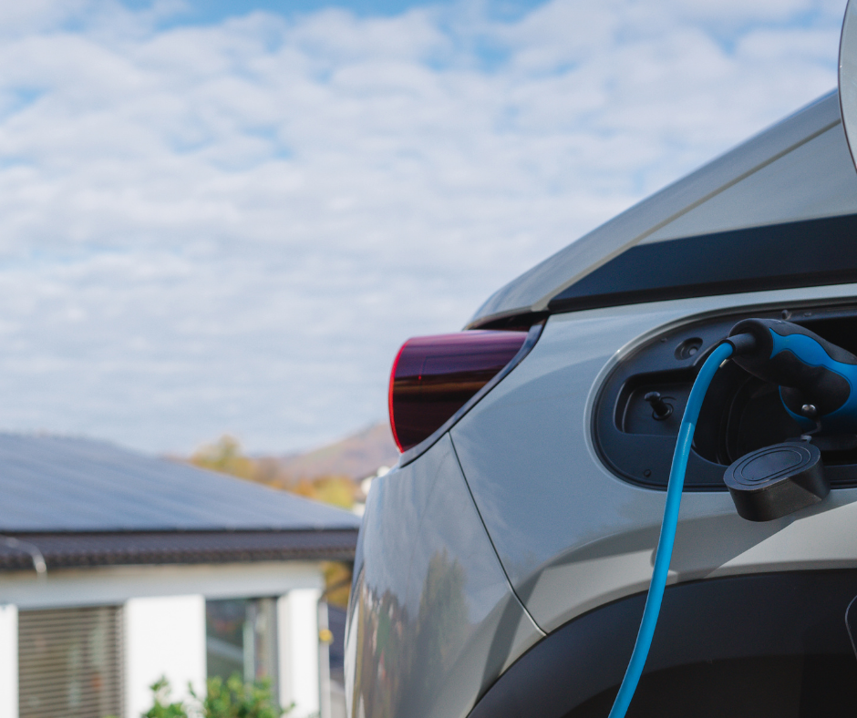 Ein E-Auto was auflädt vor einem modernen Haus mit einer Solaranlage und einer Wärmepumpe