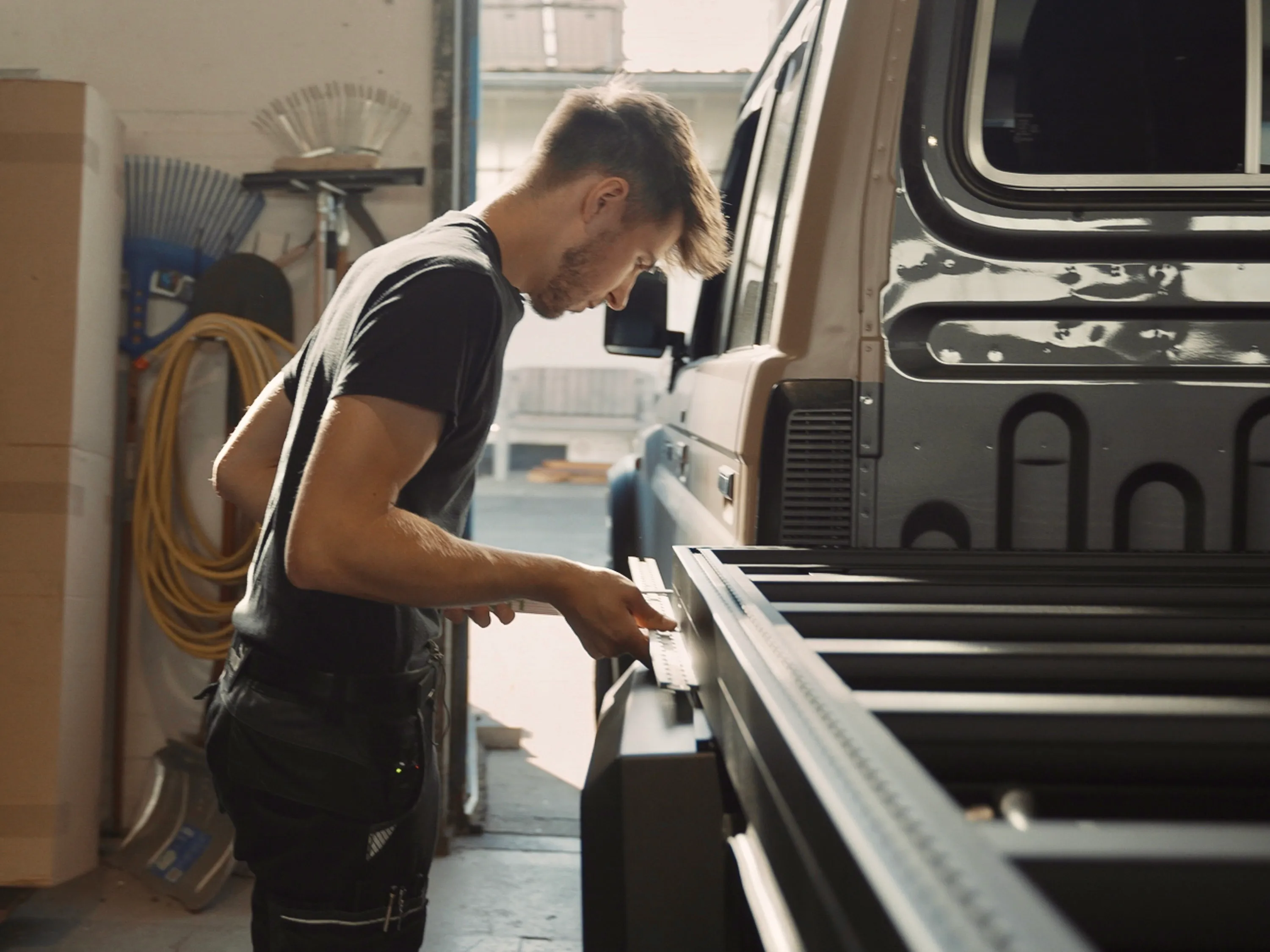 Mann montiert oder überprüft eine Pick-up-Pritschenkabine in einer Werkstatt.