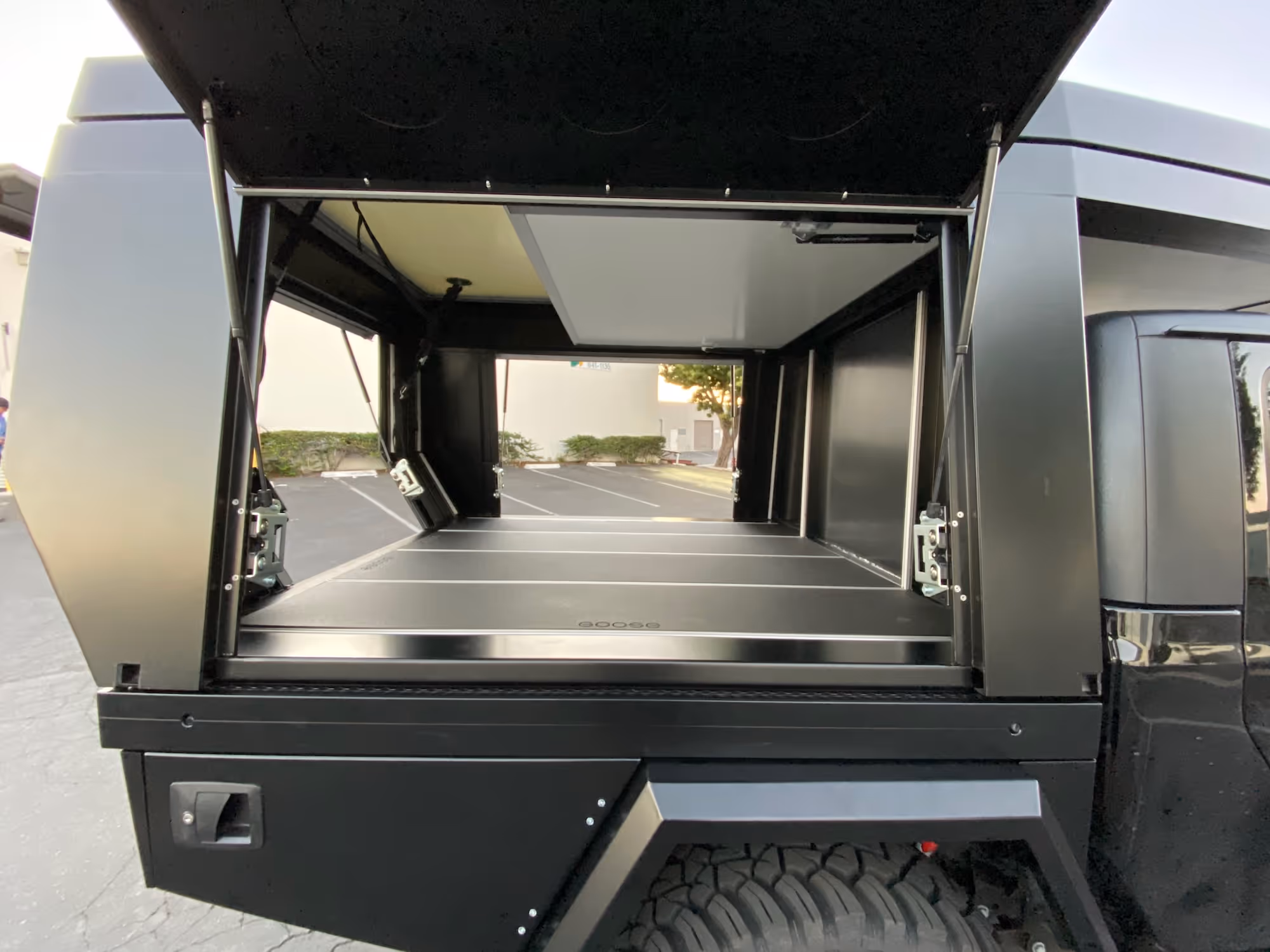 Offener Ladebereich eines schwarzen Geländewagens mit robustem Reifen und Kofferraumklappe nach oben geöffnet.