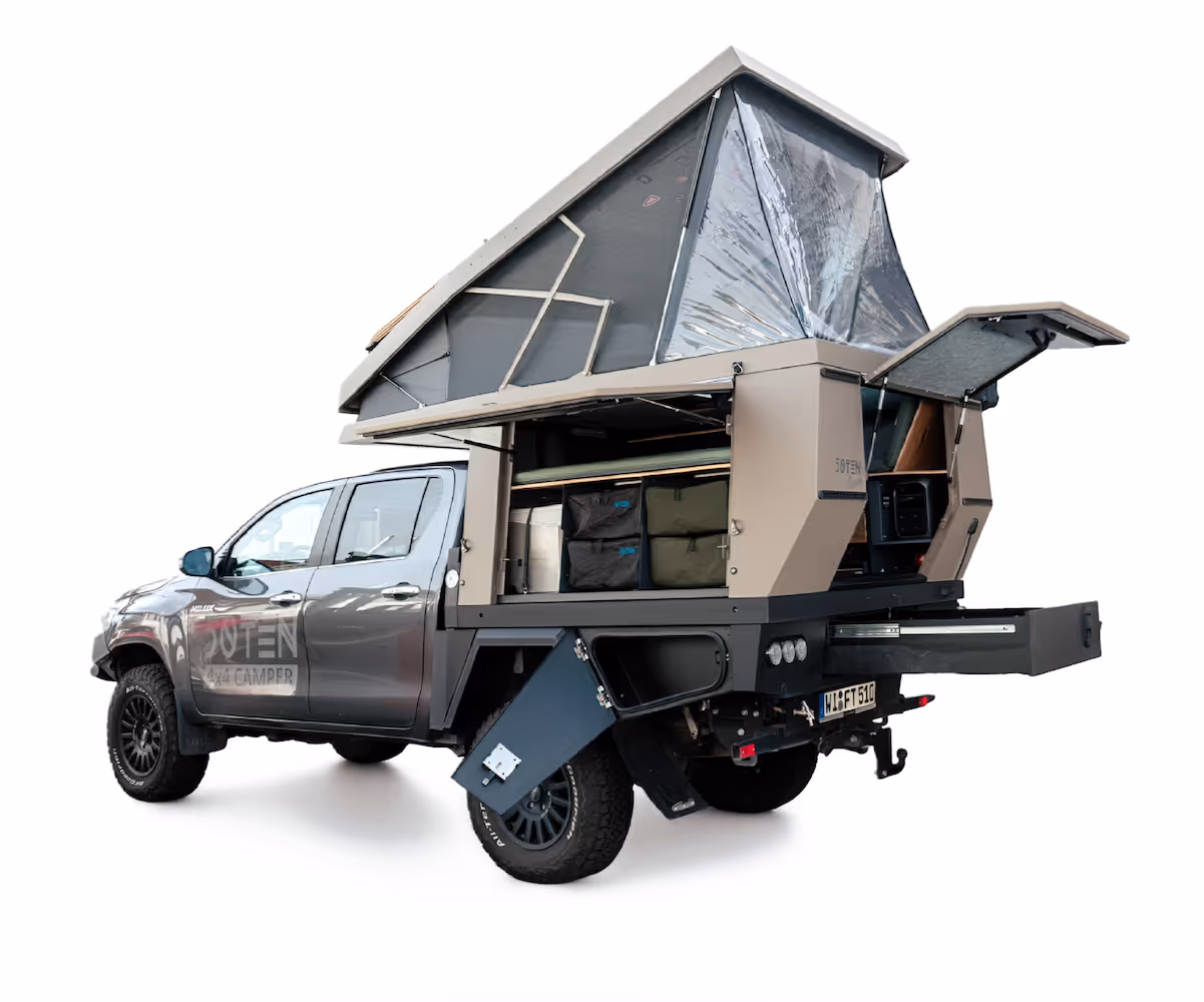 Grauer 4x4-Pickup mit hochgeklapptem, beigen Camping-Dachzelt und geöffneten Staufächern im Heck.