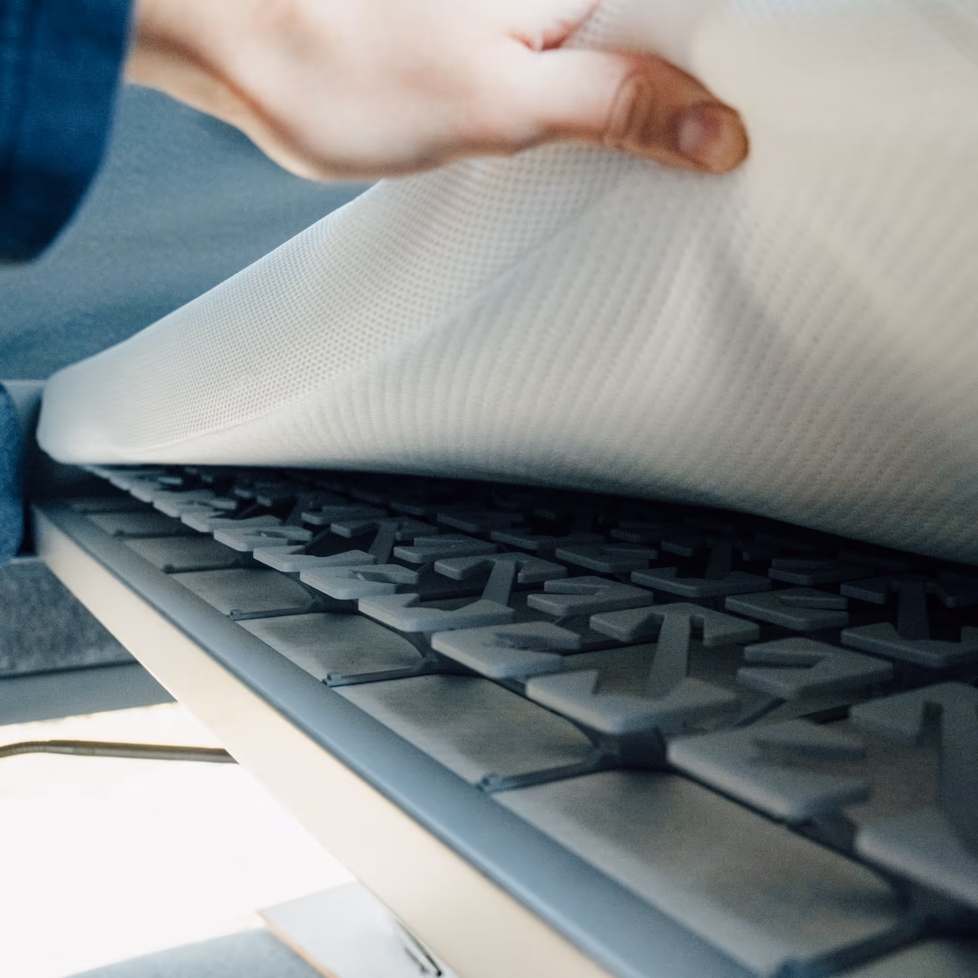 Hand hebt eine Matratze an, die eine Schicht mit sternförmigen Kissen darunter offenbart.