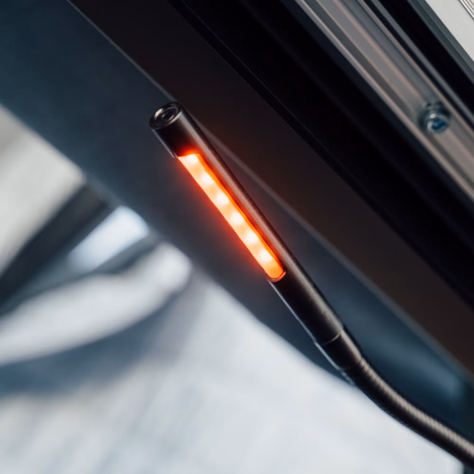 Nahaufnahme eines gebogenen schwarzen LED-Lichtbalkens mit orangen Leuchtpunkten.