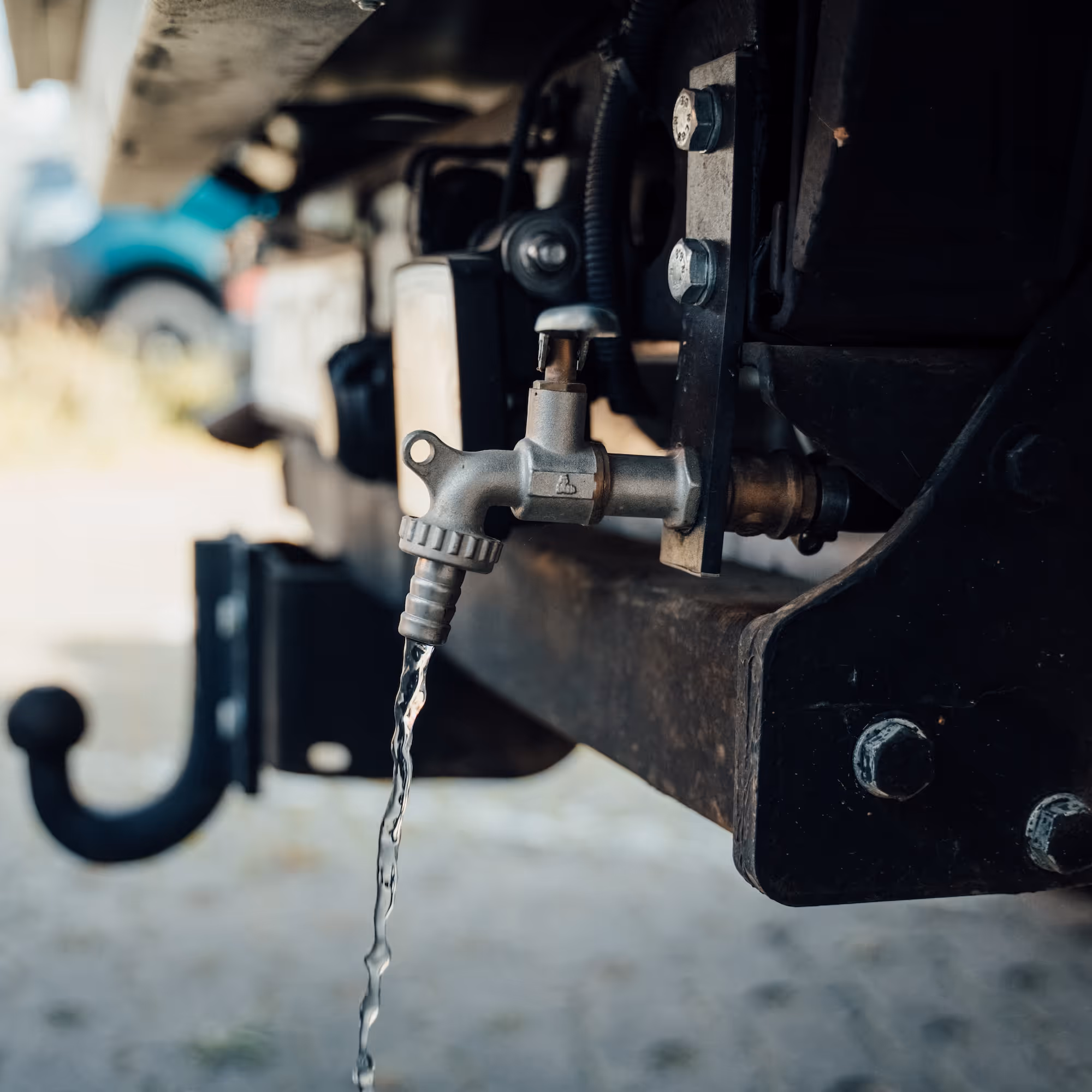 Wasser läuft aus einem grauen Metallwasserhahn, der an einer Anhängerkupplung montiert ist.
