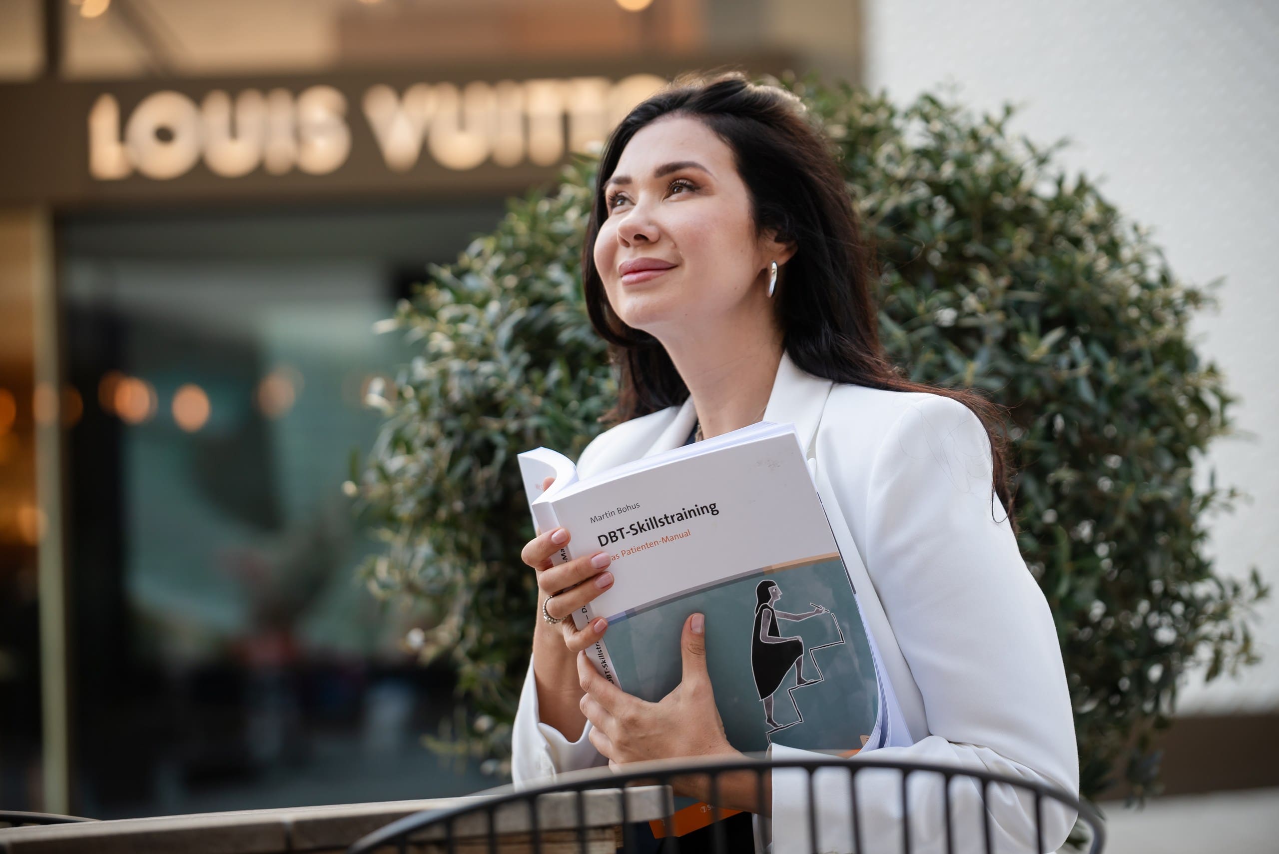 Geschäftsfotografie einer Frau mit DBT-Skillstraining-Buch vor Louis Vuitton
