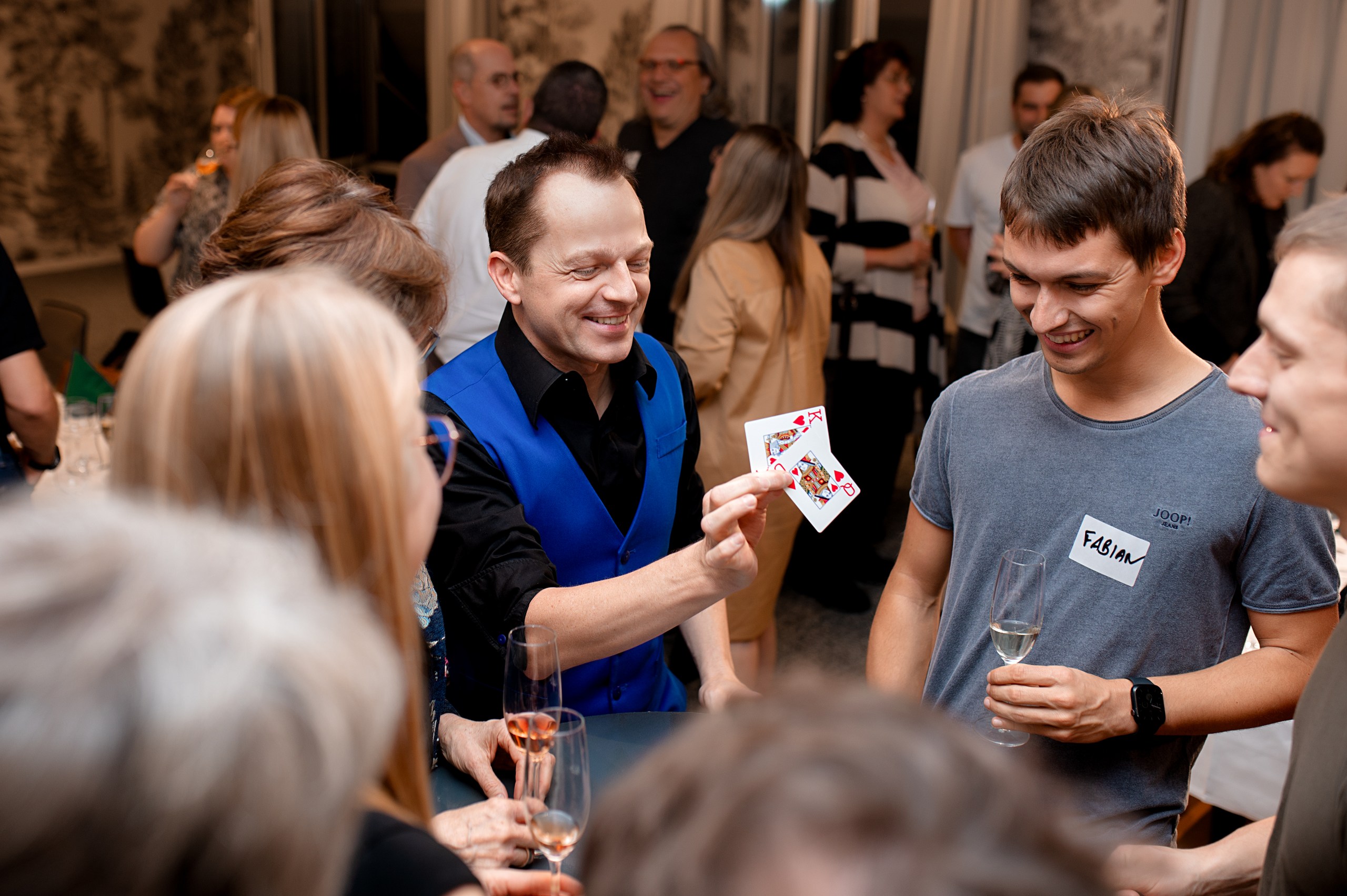 Geschäfts-Fotografie: Zauberer unterhält Gäste mit Kartentrick bei Networking-Event