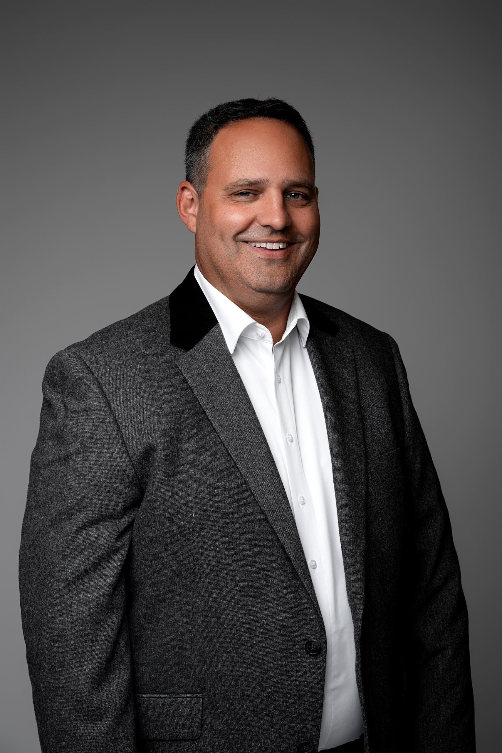 Professionelles Geschäftsportrait-Fotografie von lächelndem Mann in grauem Anzug