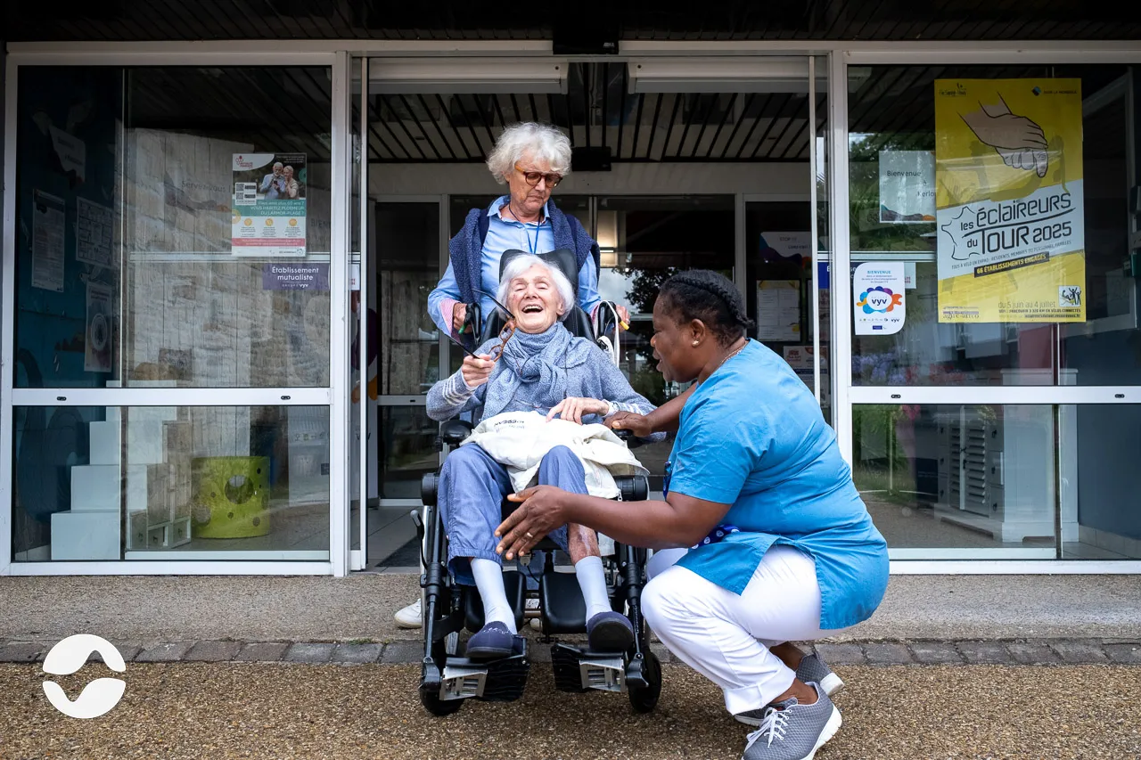 Caregiver with a resident and her daughter outside, before going for a walk.