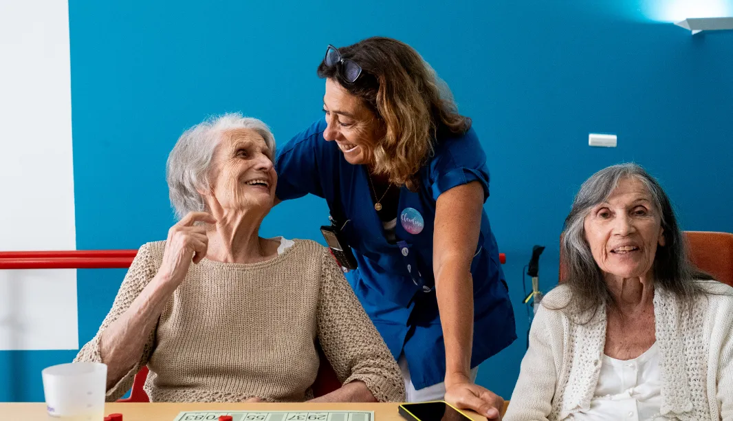 Caregiver with residents in the common room and the Orikio box in the background.