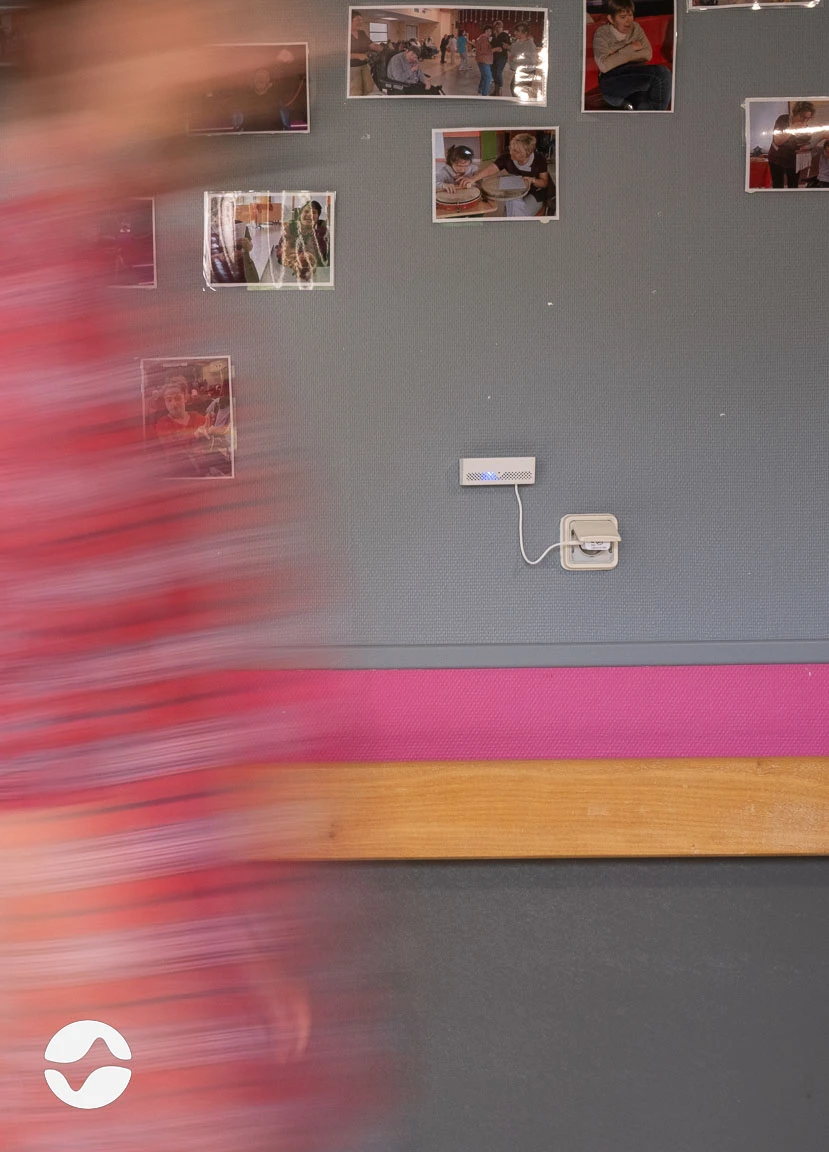 Photo du boîtier orikio branché dans un couloir de MAS, avec quelqu'un qui passe devant.