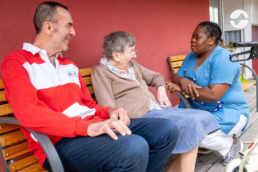Soignante avec une résidente et sa fille dehors, avant de partir en balade.