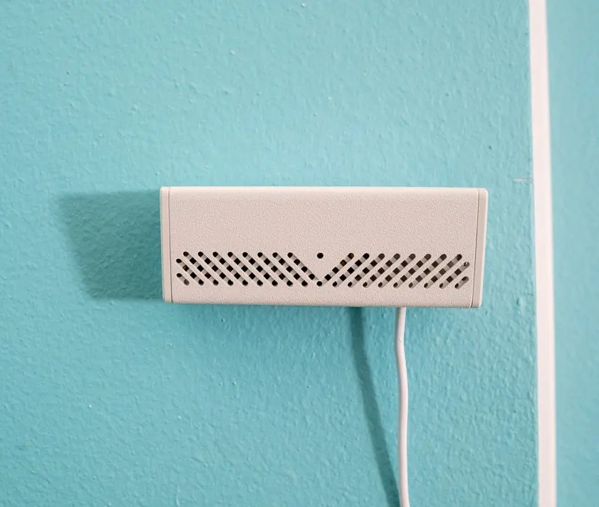 Photo du boîtier sur un mur turquoise.