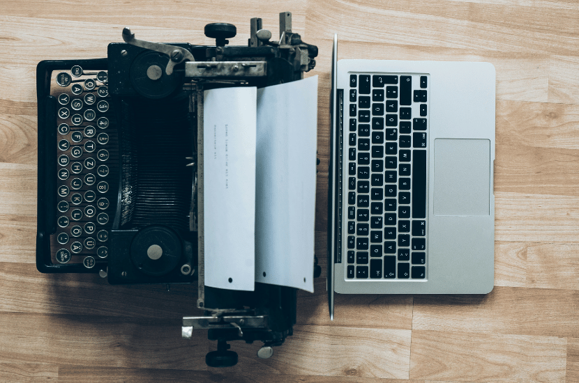 An antique typewriter beside a modern laptop, visually contrasting legacy systems with digital transformation and technology modernization.