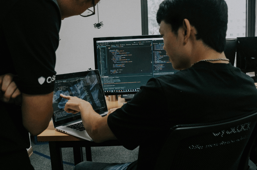 Two UX designers collaborating at a computer, reviewing interface designs and discussing user experience improvements.