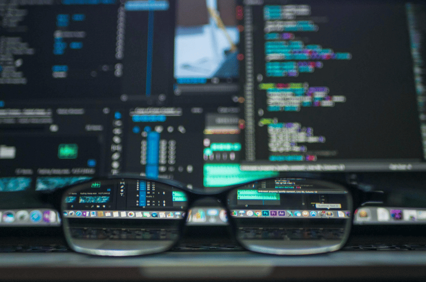 A computer screen with glasses in front, symbolizing meticulous quality assurance (QA) testing and detailed software inspection.