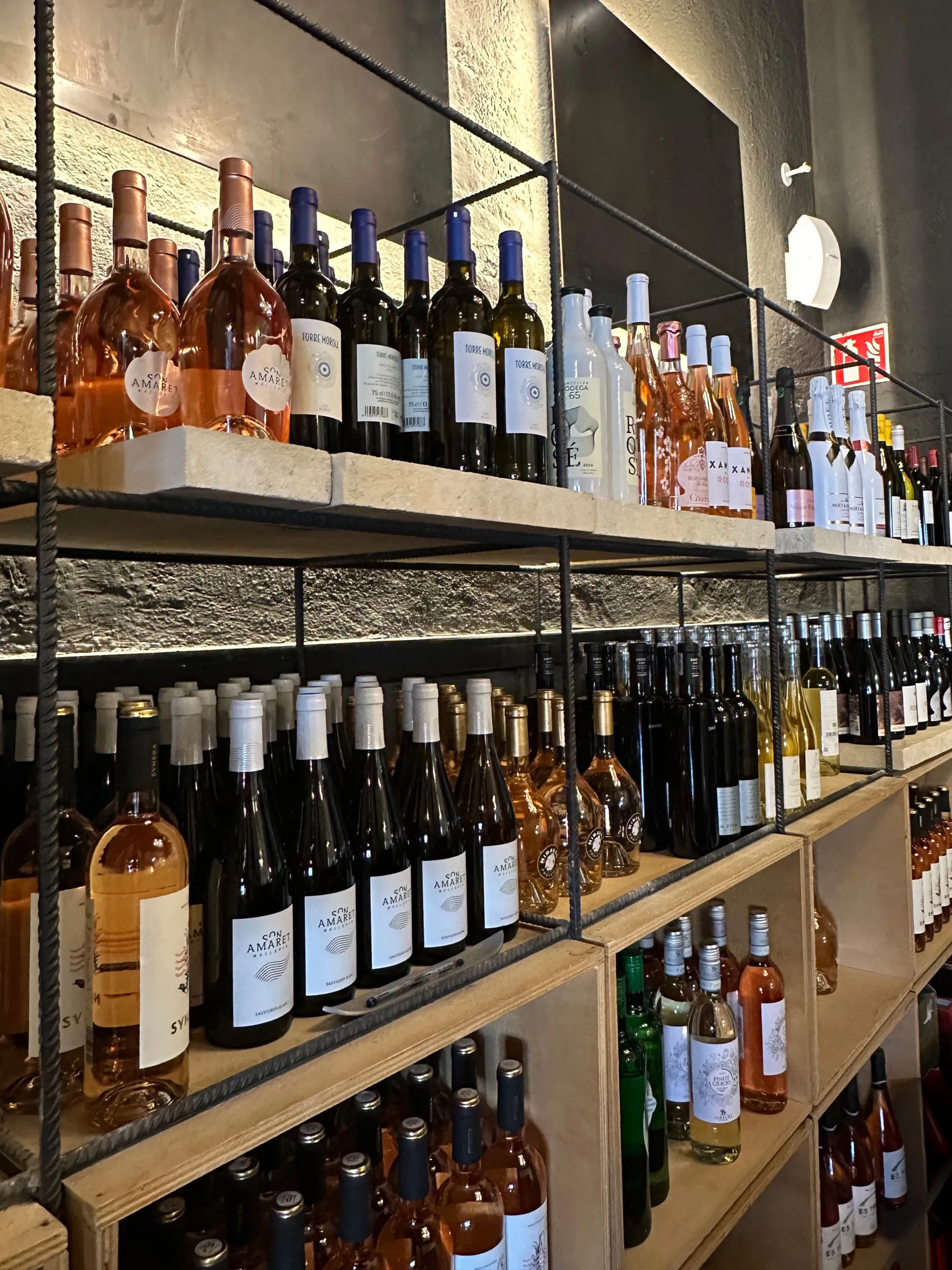 Wine bottles displayed on shelves in a well-lit, rustic storage area