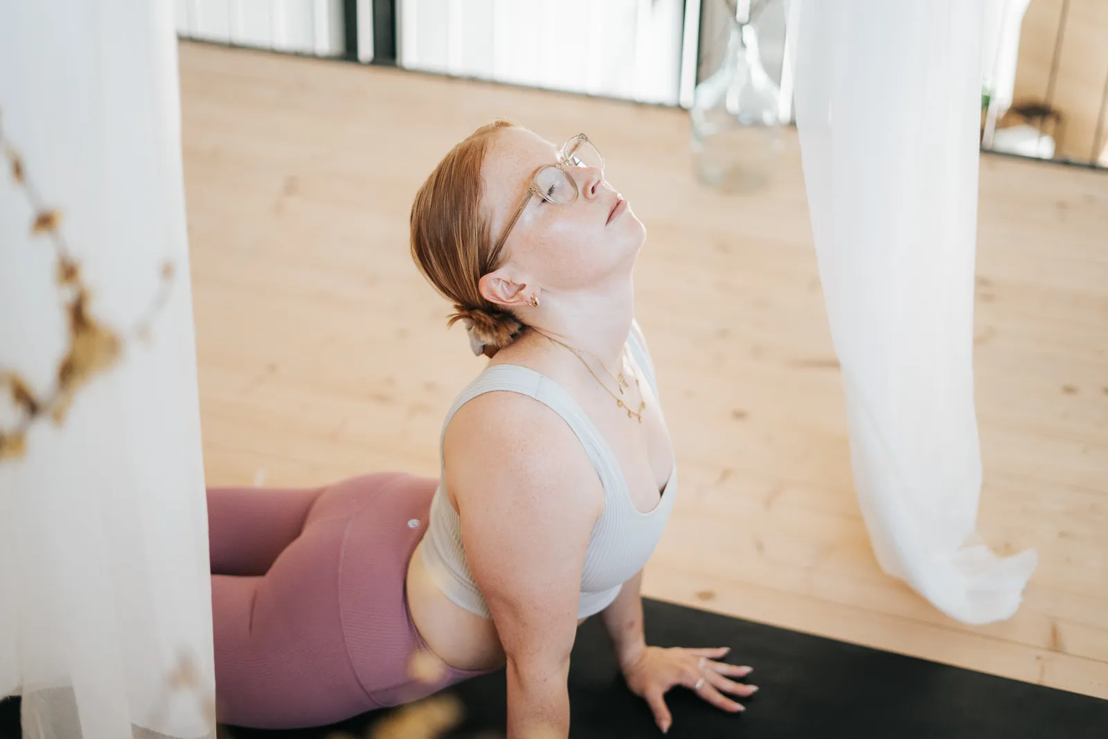 Frau übt die Kobra-Pose (Bhujangasana) im Hatha Yoga in einem hellen Yogastudio in St. Pölten, Niederösterreich.