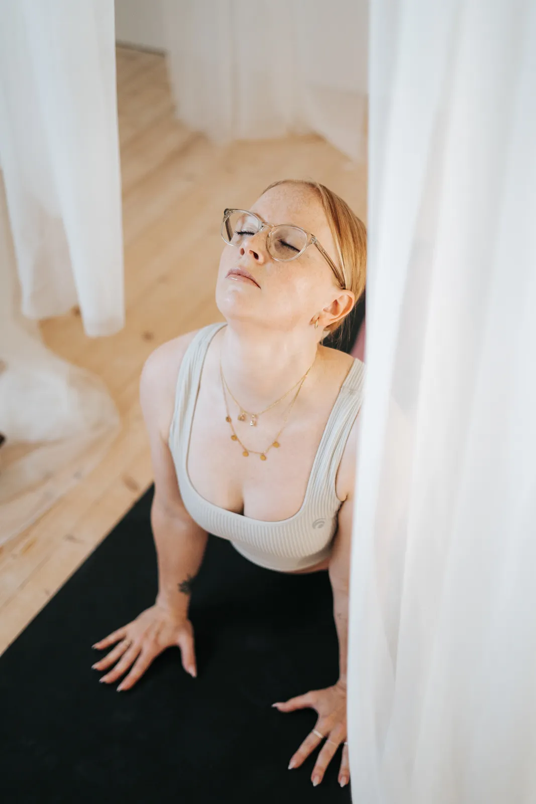Frau in der Kobra-Pose auf Yogamatte, umgeben von weißen Tüchern – Yoga und Achtsamkeit in Niederösterreich.