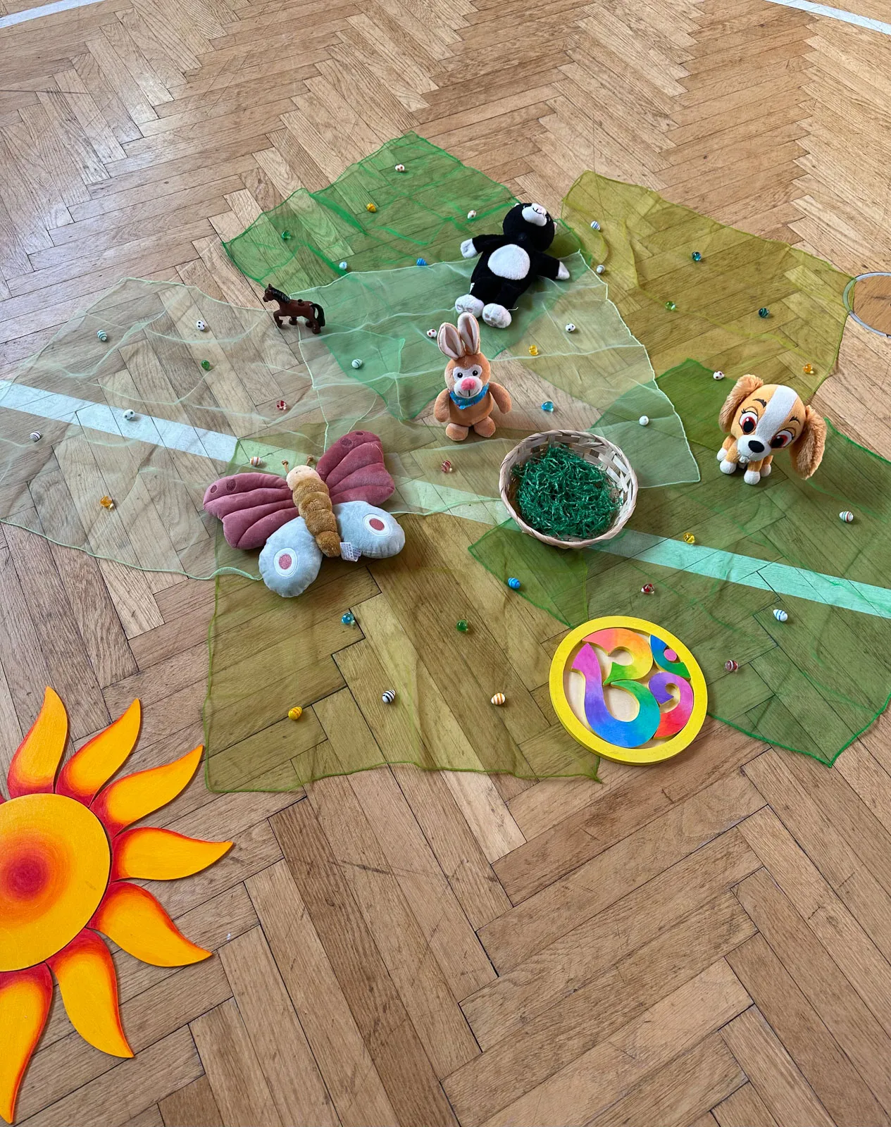 Tücher, Sonne, Schmetterlng und weitere Materialen liegen auf dem Boden für Kinderyoga Einheit zum Thema Frühling