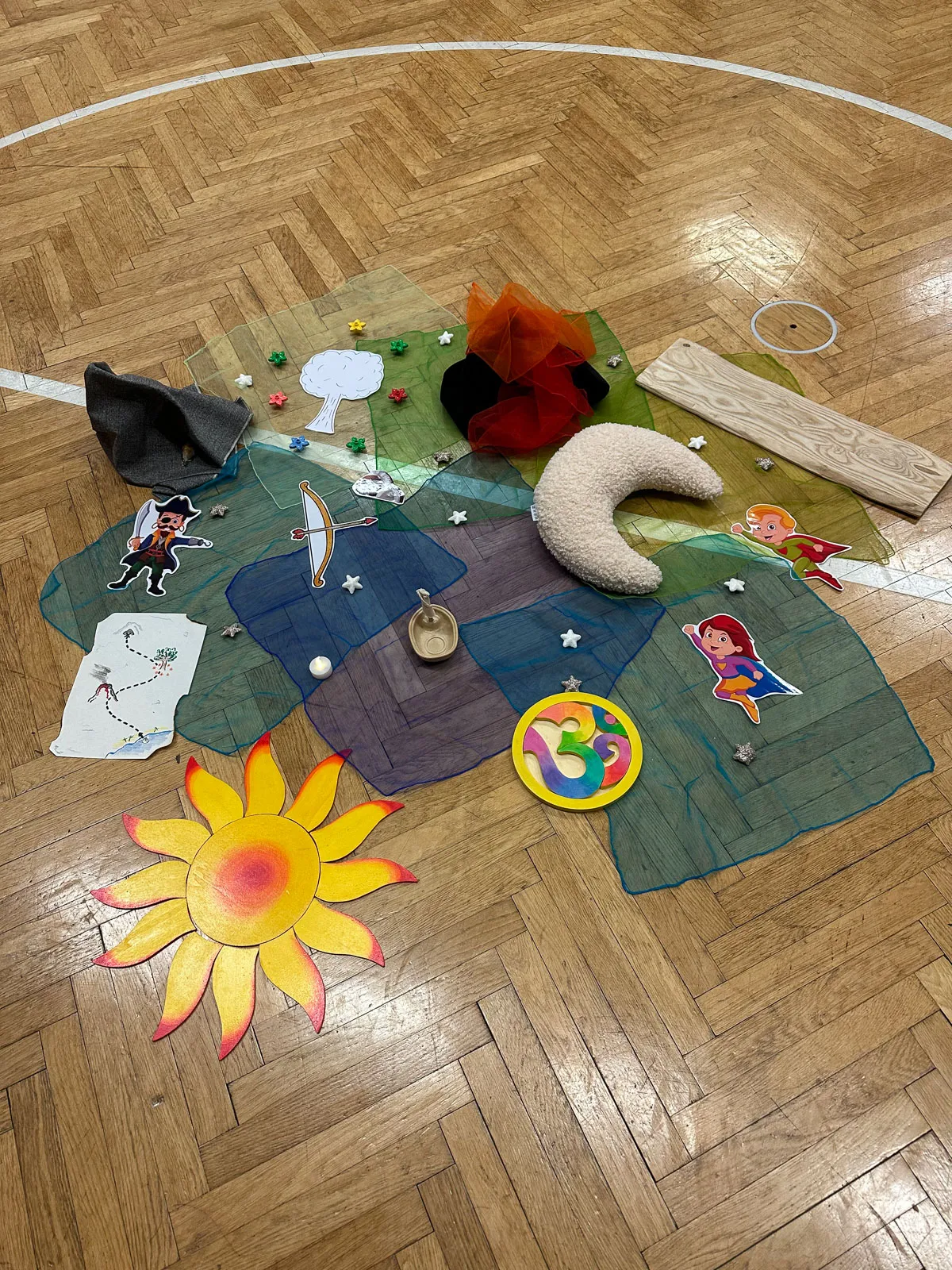 Tücher, Sonne und weitere Materialen liegen auf dem Boden für eine Schatzsuche