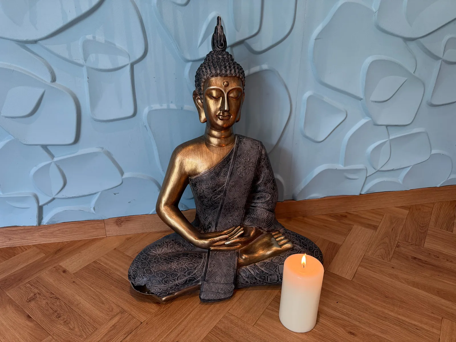 Farbaufnahme einer goldenen Buddha-Statue mit Kerze im Yogaraum, perfekt für Achtsamkeit.