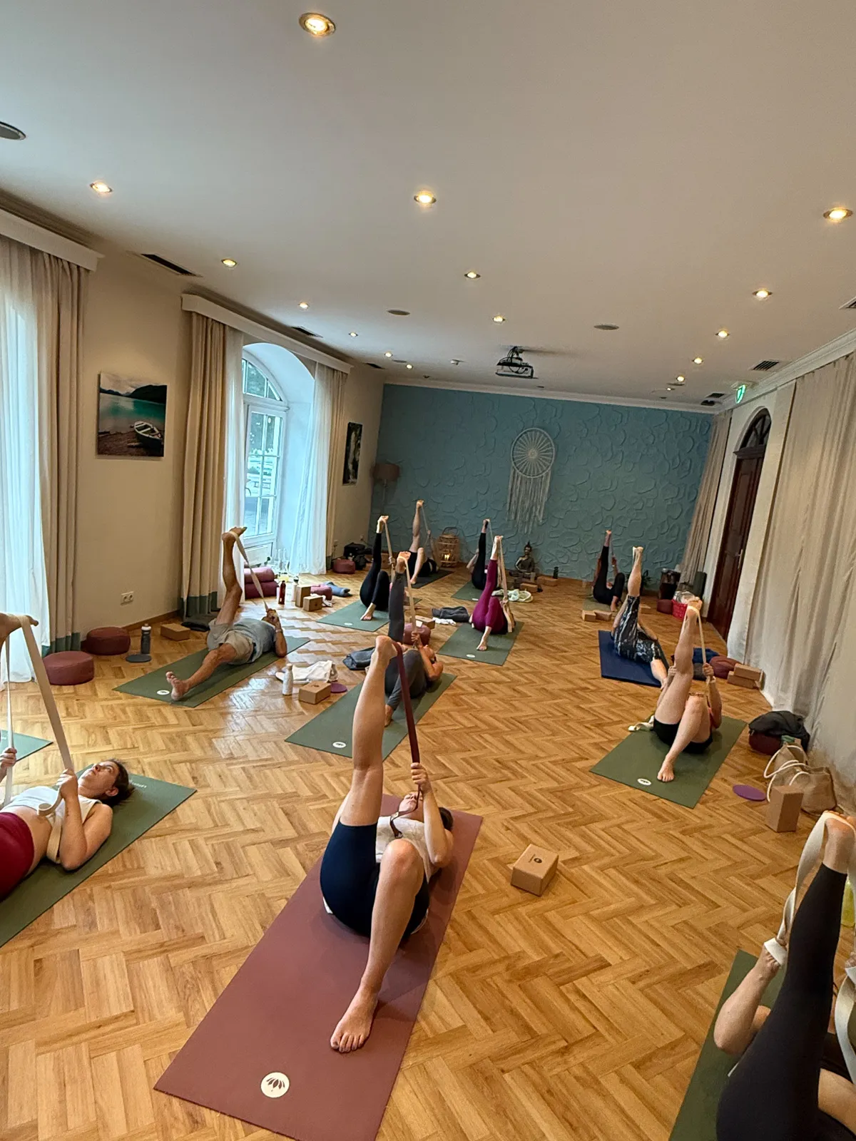 Teilnehmer im Yogaraum während einer Dehn- und Meditationsübung mit Yoga-Gurten beim Retreat.