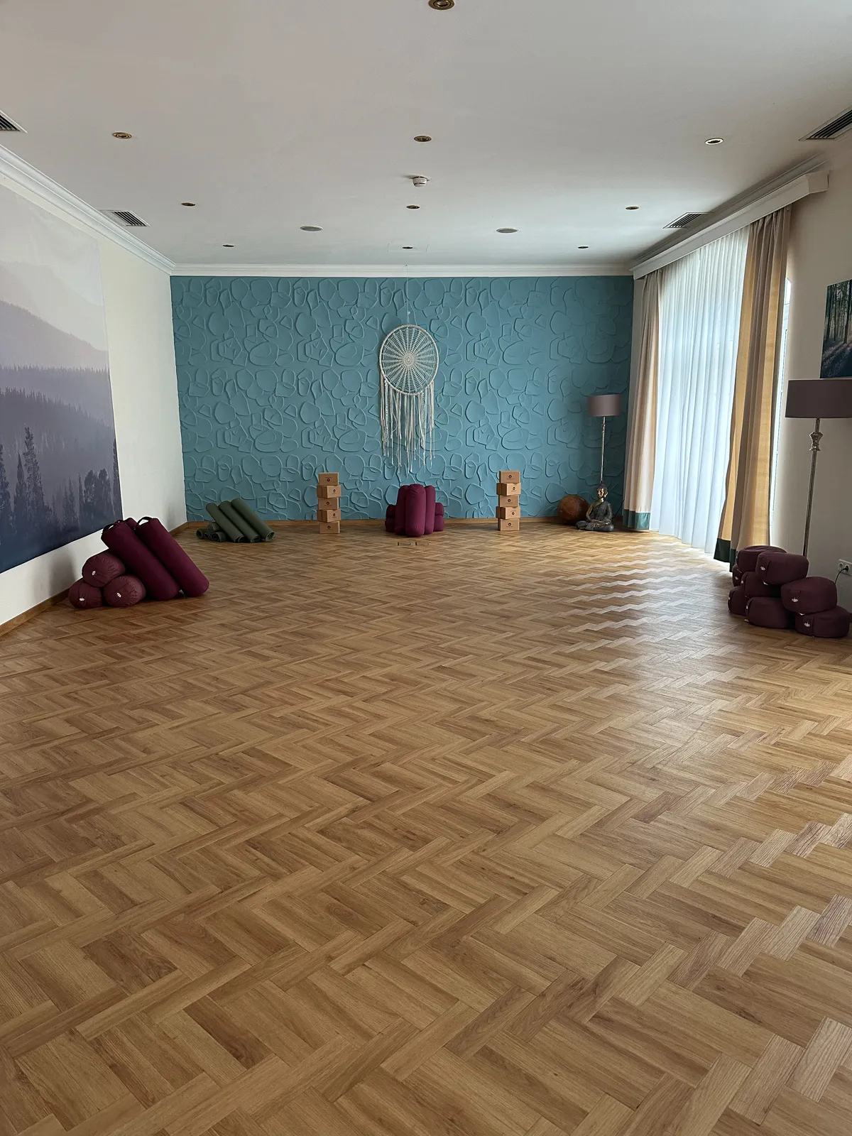 Heller Yogaraum mit Holzfußboden, Yoga-Matten und Meditationskissen für ein Retreat-Wochenende vorbereitet.
