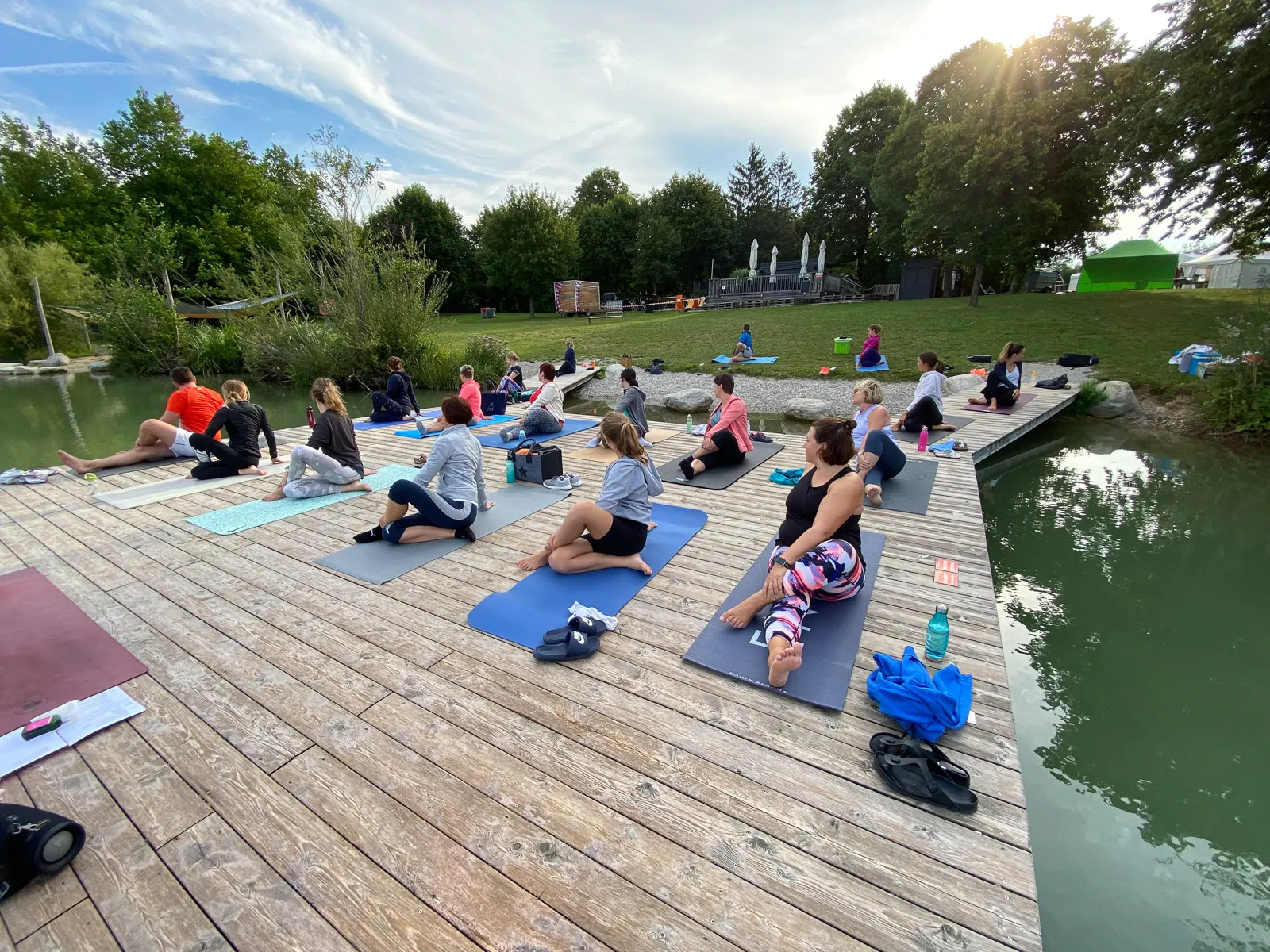 Teilnehmer üben Yoga-Drehhaltungen auf Matten am Steg des Ebersdorfersees.