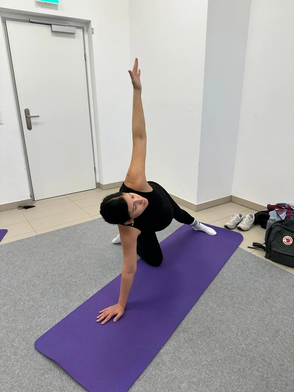 Schwangere Frau auf der Yogamatte in einer sanften Drehhaltung, unterstützt durch Achtsamkeit und kontrollierte Atmung.