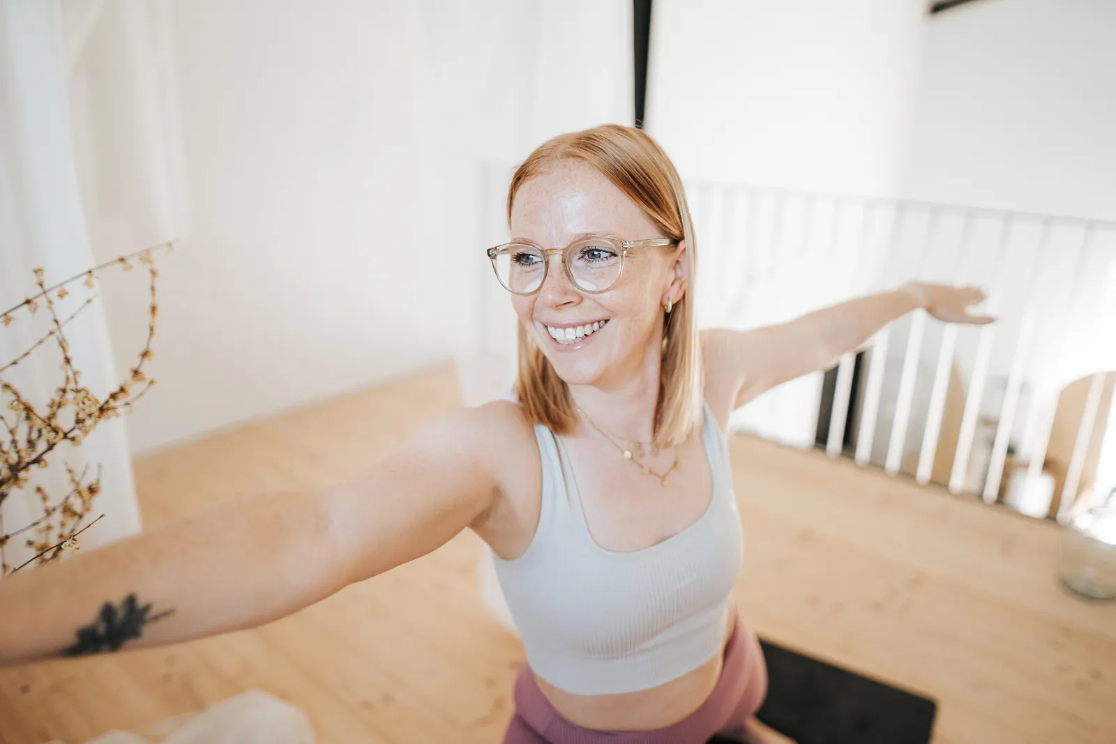 Frau beim Yoga, die lächelnd in der Krieger-Pose die Arme ausstreckt – Yogaübungen in St. Pölten und Melk, Niederösterreich.