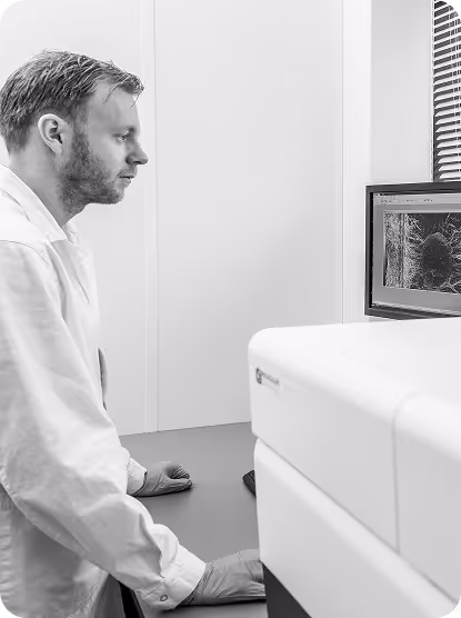 Researcher in white coat analyzing image on computer screen in laboratory