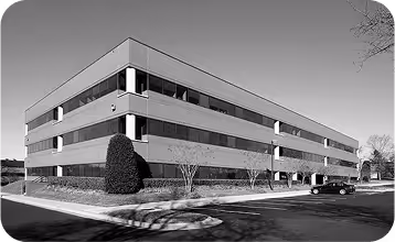 Modern rectangular office building with horizontal lines and landscaped entrance