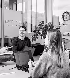 Two colleagues discussing work in modern office with plant and glass walls