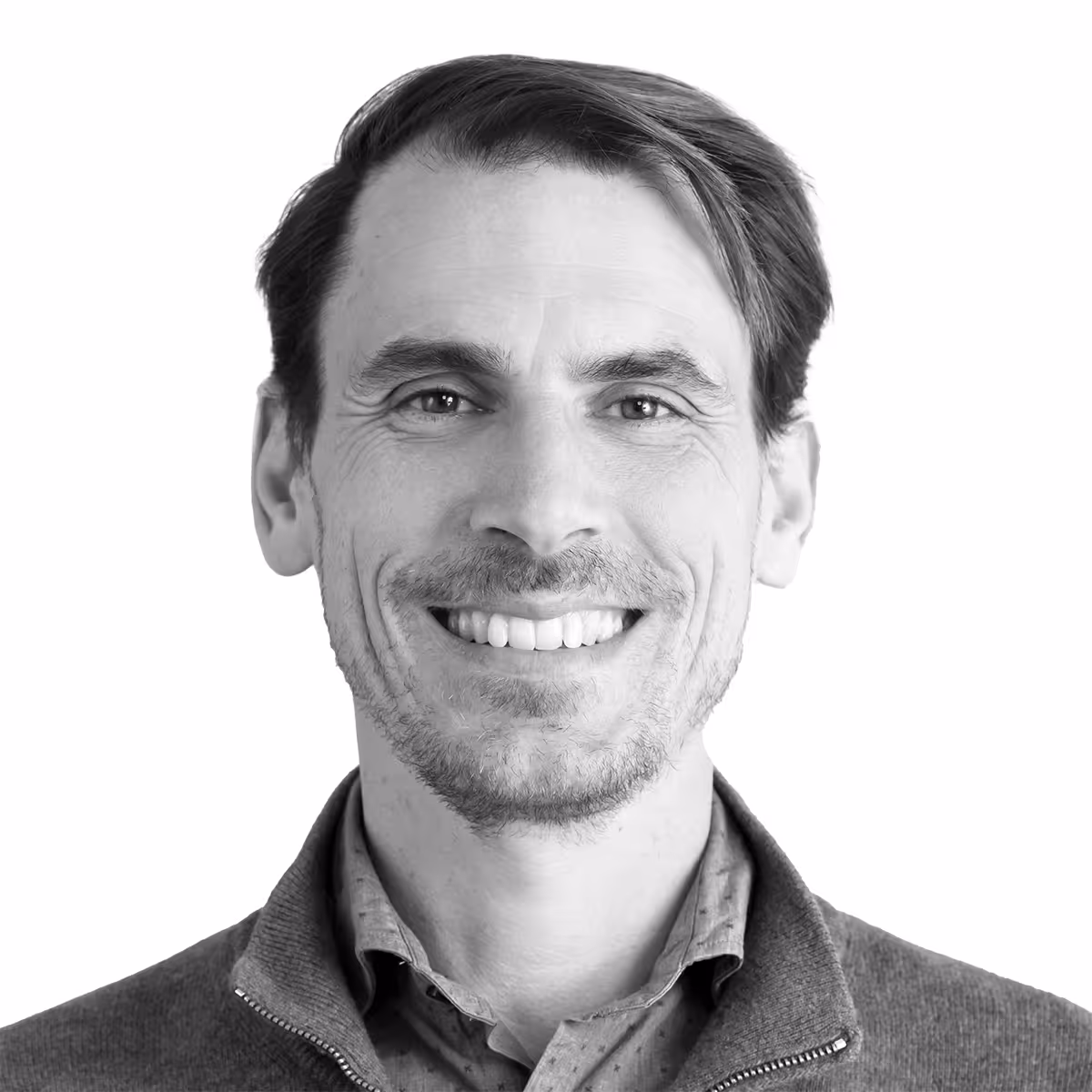 Smiling adult in black and white headshot wearing layered clothing