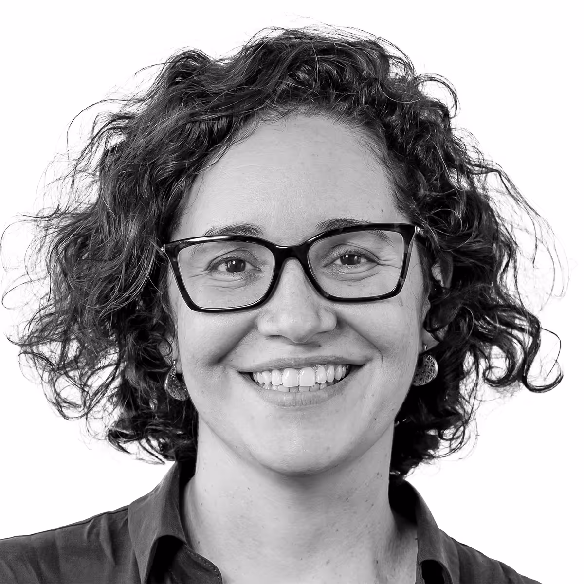 Smiling person with curly hair and glasses in black and white portrait